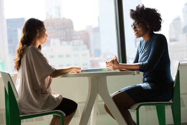 Landlord and tenant talking across a small table with city view in background